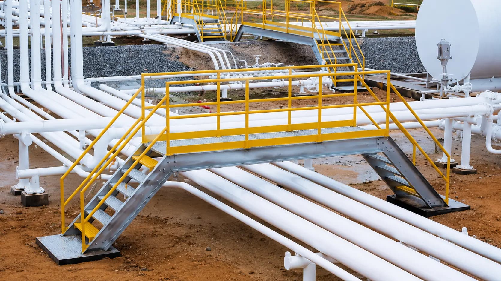 Yellow-railed access stairs and platform over piping at an energy facility