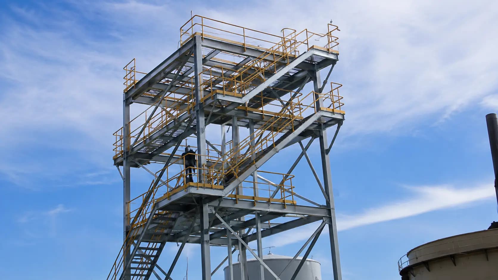 Tall steel access tower and platform structure at an industrial site