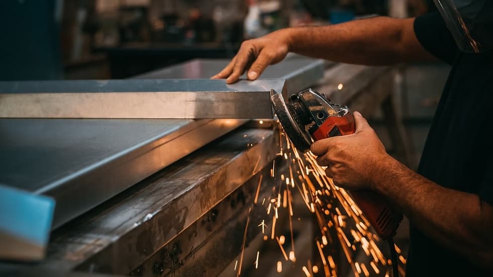 Worker cutting fabricated steel with sparks in the shop