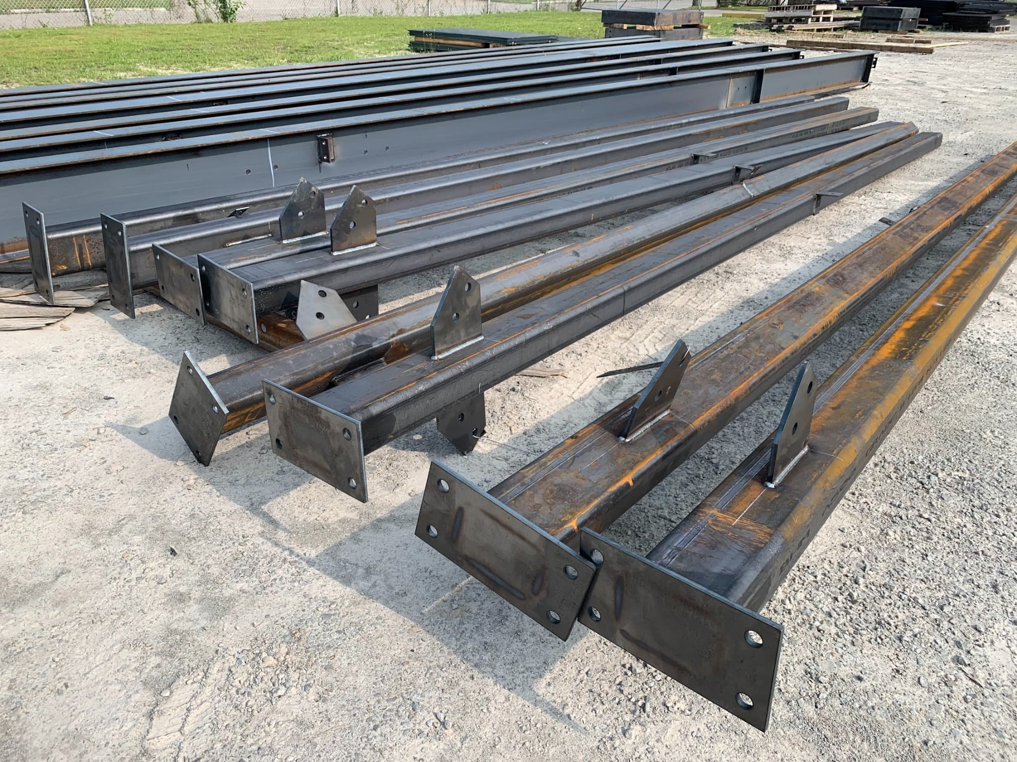 Fabricated steel members and brackets staged on gravel