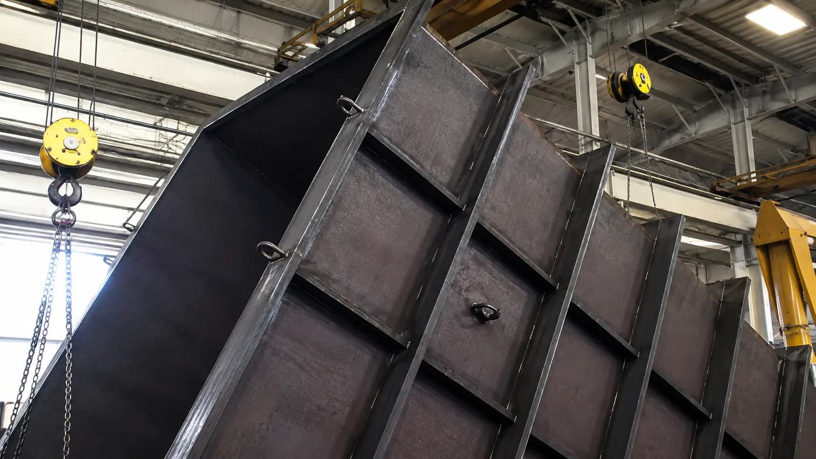 Large fabricated steel weldment with internal ribs lifted by a crane hook