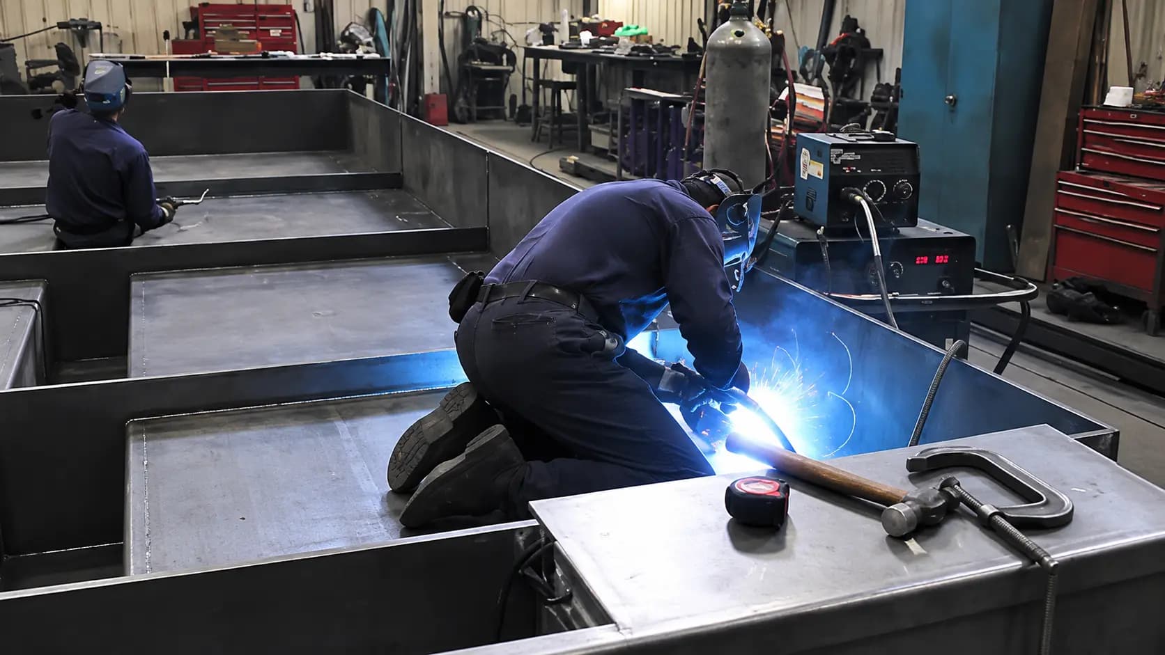 Welder joining a fabricated steel base in the shop