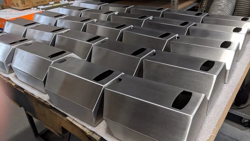 Rows of formed stainless steel sheet metal components on a table